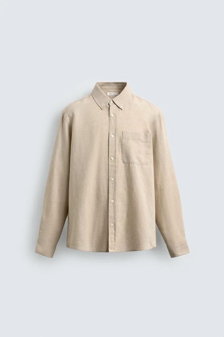 Man wearing a sand-colored band-collar linen button-up shirt with the sleeves rolled up